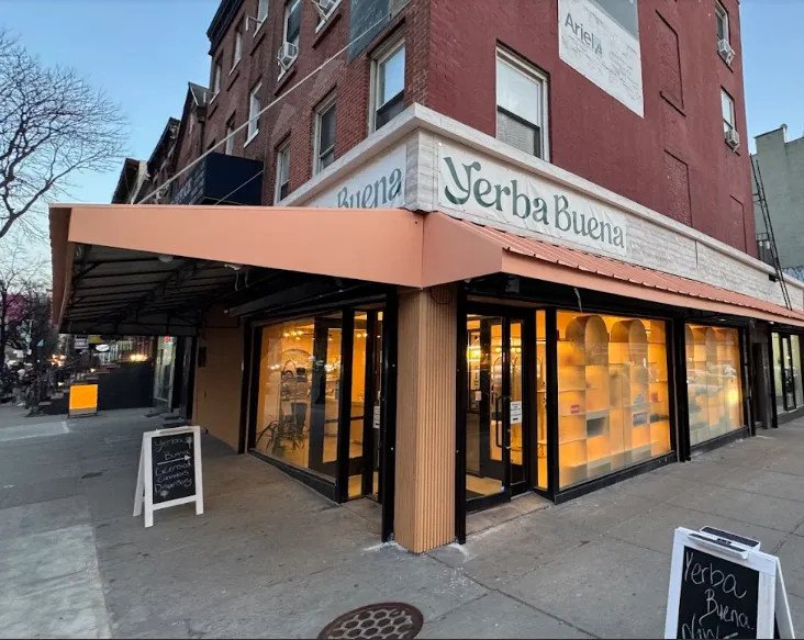 A photo of the exterior of the Yerba Buena Cobble Hill location, showing the beauty and poise of the exterior of the store at open, including an awning styled after the Italian architecture found in the neighborhood of the Dominican Founders.